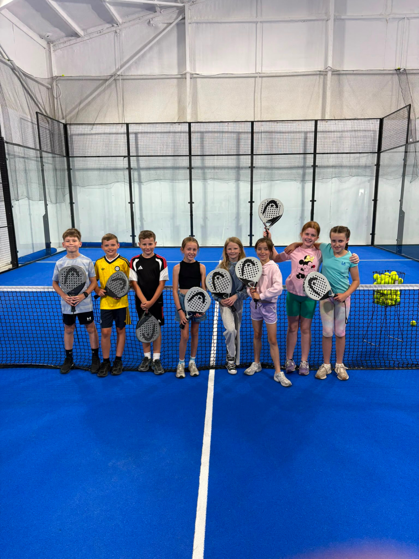 Children lined up with padel rackets after a coaching session at Poplars Padel