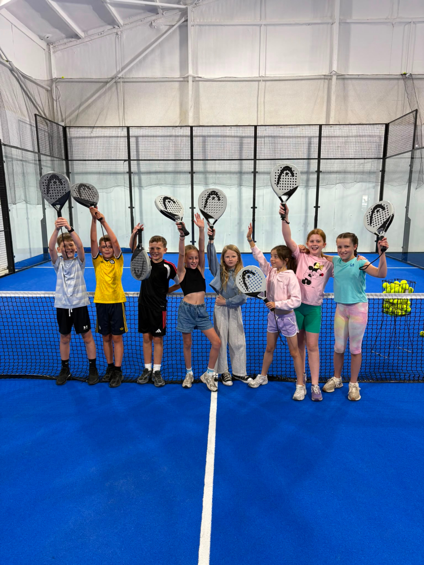 Junior padel group holding rackets up at the net at Poplars Padel near Goole